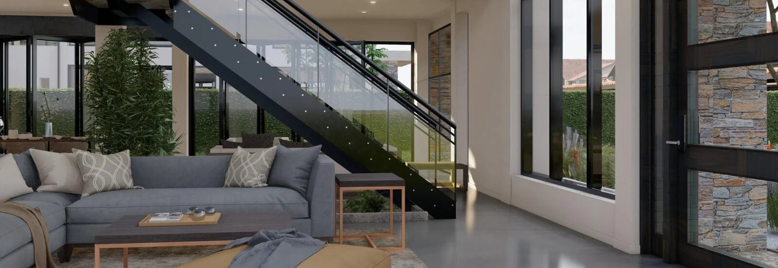 A wide interior rendering of a modern living room featuring a gray sectional sofa adorned with patterned cushions, a small wooden coffee table, and a soft throw. The space includes a stylish metal staircase with glass balustrades that lead upstairs, contributing to the open, airy feel. Large windows and sliding glass doors fill the room with natural light, highlighting the stone accent walls and potted greenery, creating a harmonious blend of indoor and outdoor elements.