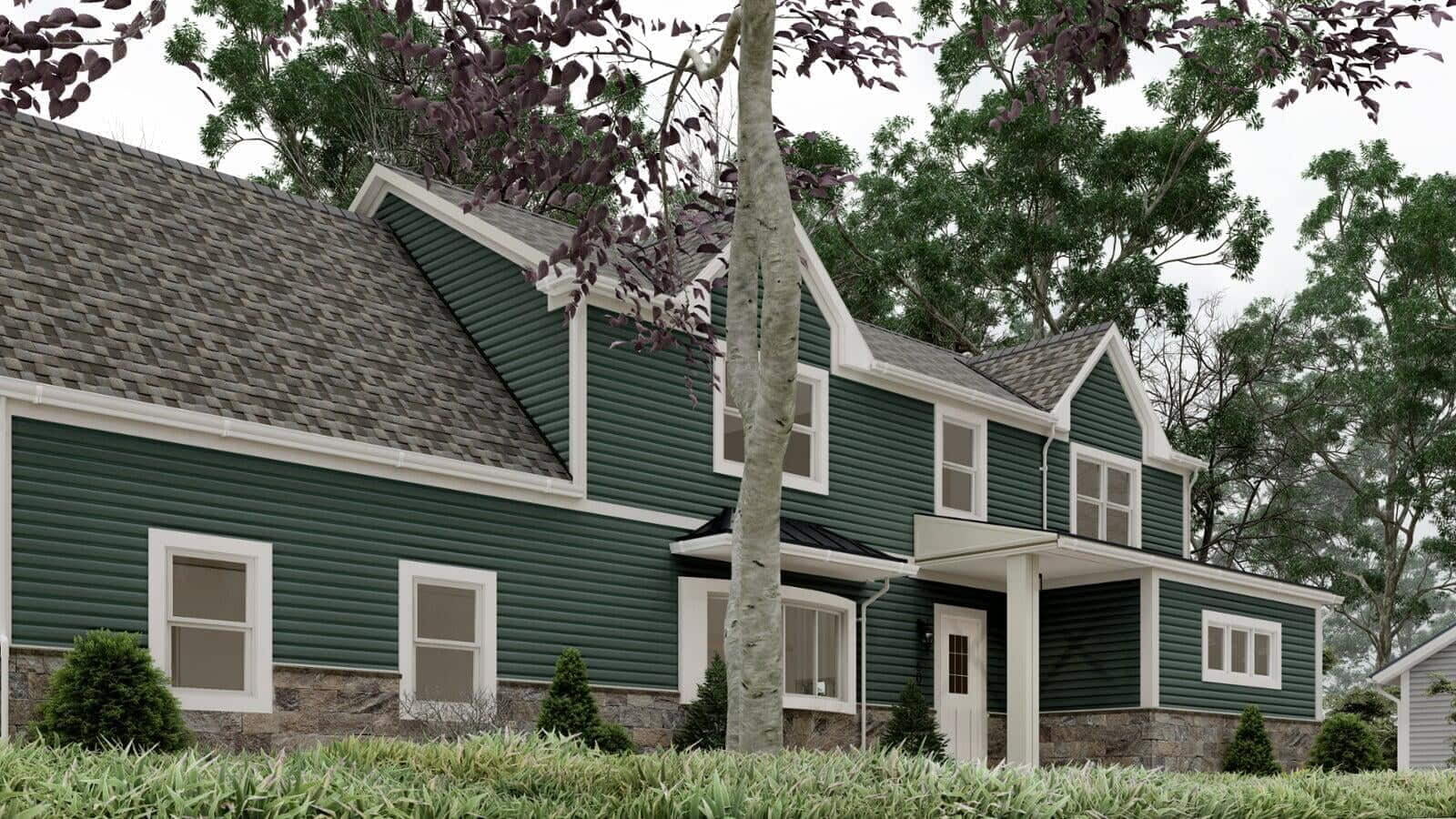 Side view of a green modular home with white trim, featuring a double garage and a landscaped yard with various shrubs.
