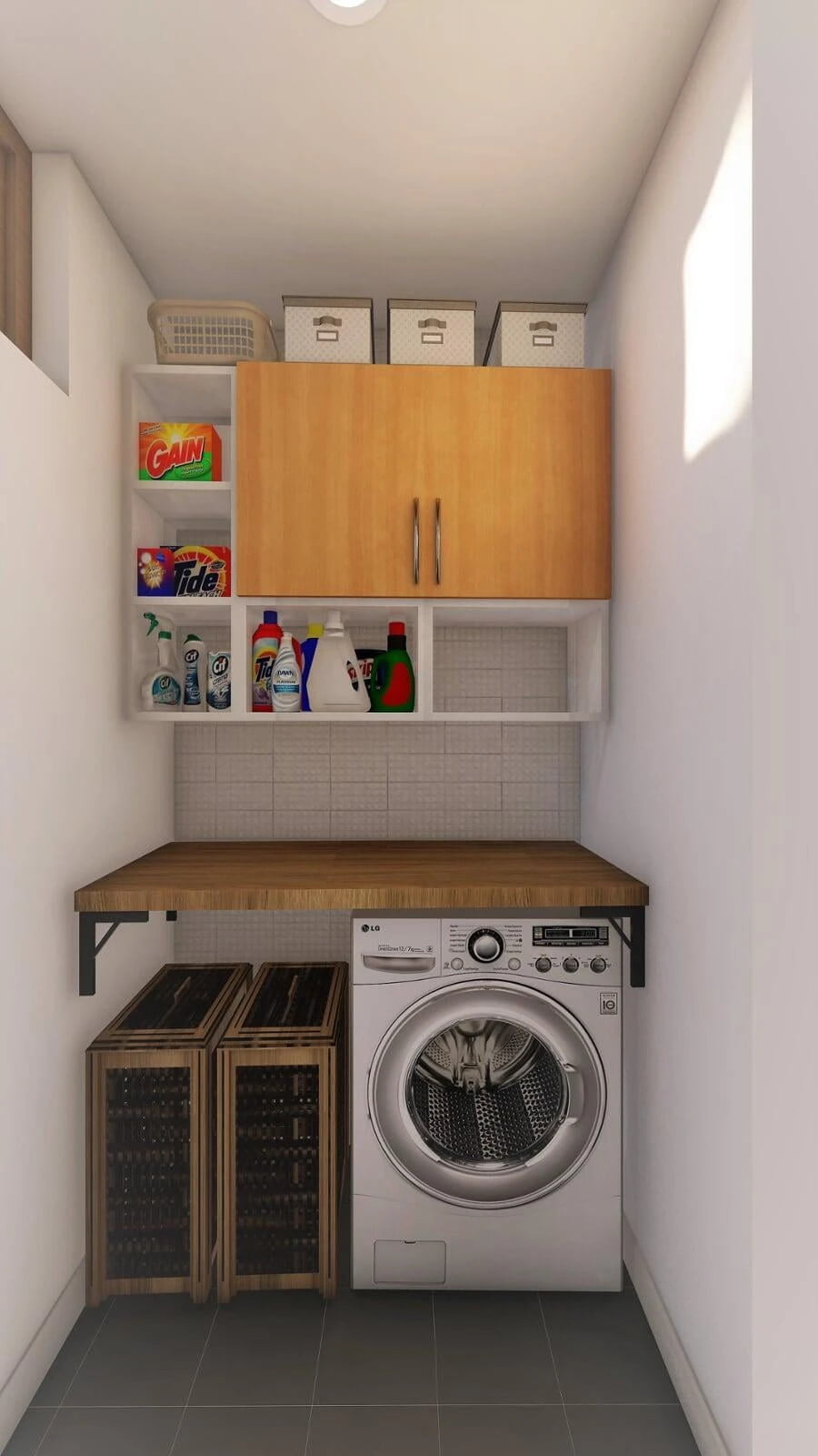 A narrow laundry room featuring a front-loading LG washing machine on the right. Above the washer, there's a wooden workbench with a textured gray countertop. Directly above, two wooden wall cabinets store various cleaning supplies, including bottles of Tide, Gain, and other household cleaners. On the top shelf, there are labeled storage boxes and a detergent box. To the left, two wooden crates possibly for storage sit on the floor. The room has a simple white ceiling with a single light fixture and tiled walls halfway up